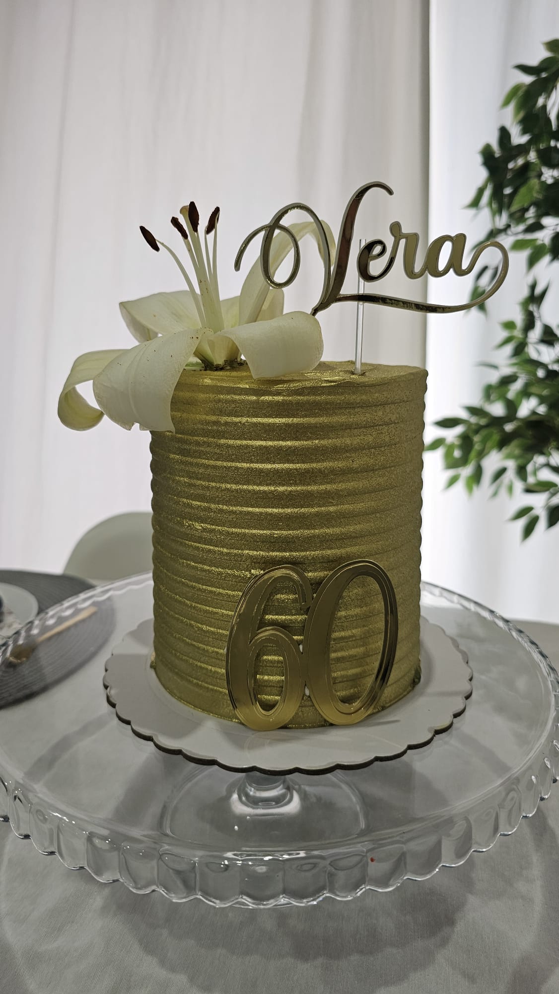 Tarta dorada de 60 cumpleaños con lirio blanco y topper «Vera»